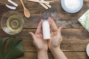 Hands holding DIY beauty product surrounded by natural ingredients