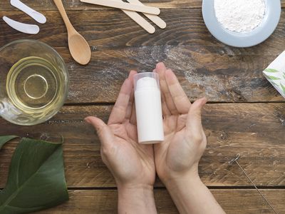 Hands holding DIY beauty product surrounded by natural ingredients