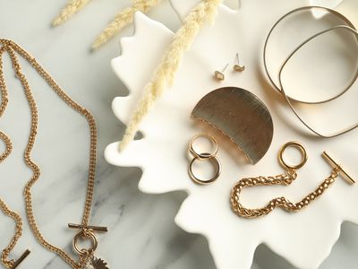 Gold jewelry laid out aesthetically on marble background
