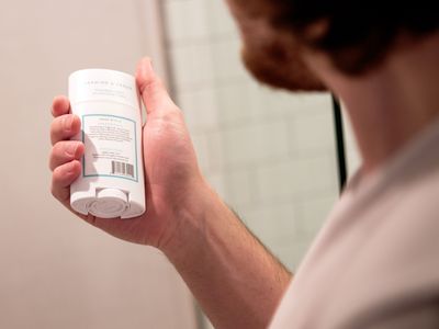 guy with beard inspects back of stick plastic deodorant to see if it's natural