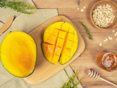 mango cut in half on cutting board with honey and oats for diy face mask 
