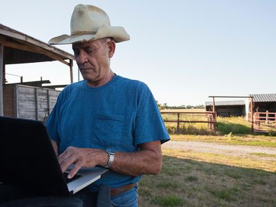 Farmer using laptop by barn