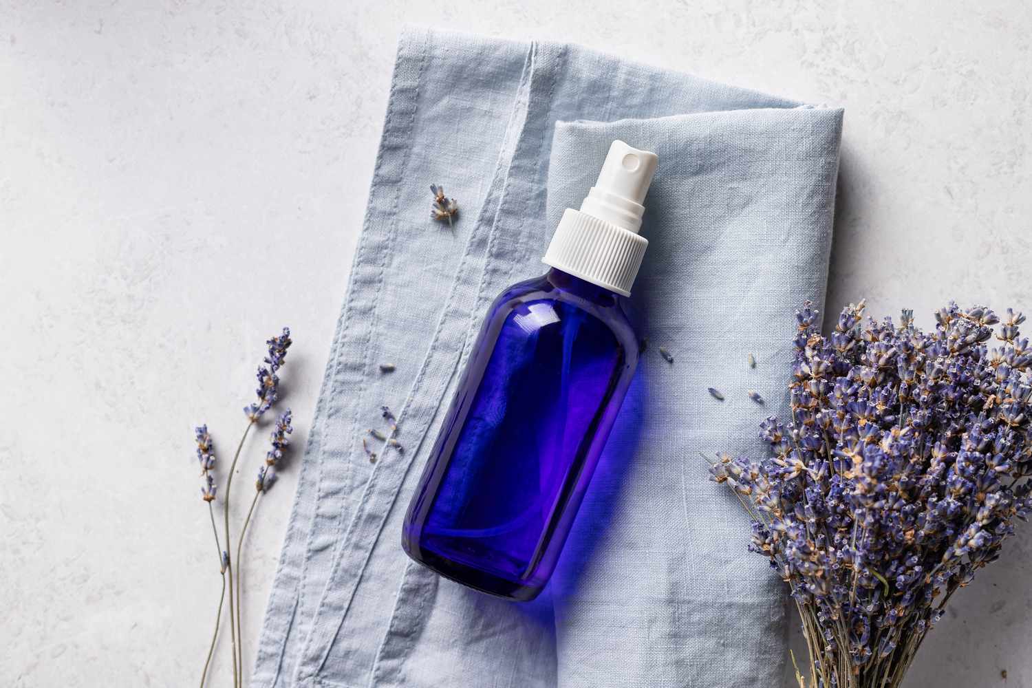 Blue spray bottle on cloth next to lavender plant