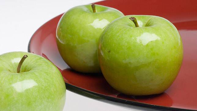 Granny Smith apples sitting on a red plate