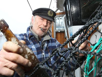 Fisherman pulling an old bottle from fishing net