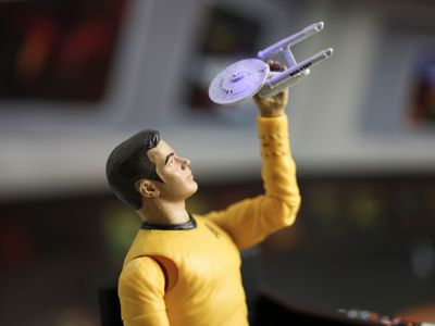 A model of James T. Kirk playing with a replica of the Starship Enterprise.