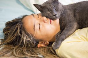 Asian teenager snuggles with her gray cat