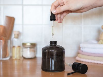 woman squeezes castor oil into brown glass jar for skin moisture