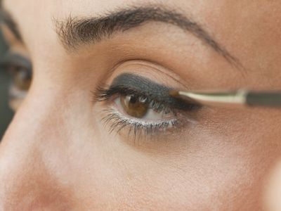Caucasian woman putting on eyeliner