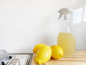 3 lemons next to a spray bottle filled with light yellow liquid on a countertop