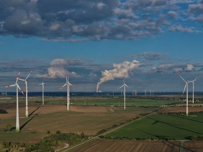 In this aerial view, wind turbines spin at a wind park as water vapour rises from cooling towers of the Kraftwerk Lippendorf coal-fired power station on September 21, 2022 near Weissenfels, Germany.