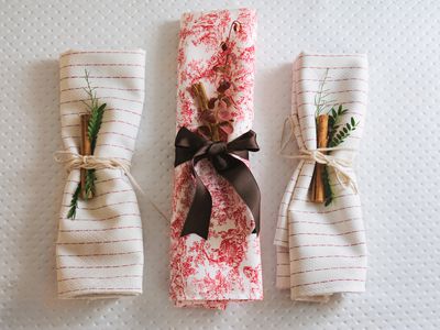 three folded napkins with holiday christmas decor and napkin rings