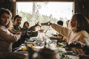 A group of people at a dinner table passing dishes to each other