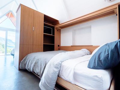 A Murphy bed in a bright sunlit room with large windows.