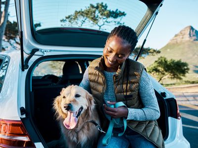 Woman and dog next to the hatchback of a car.