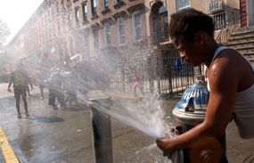 A girl directs the spray from an open fire hydrant as children try to cool off from the summer heat August 7, 2001 in the Brooklyn borough of New York City. 