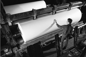 Man inspecting roll of paper in mill,