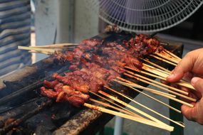 Goat meat being barbecued on sticks.