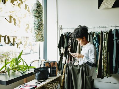 POC woman shops for clothing in fashion boutique with large window and plant