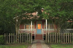 A small house with pretty shade trees in front