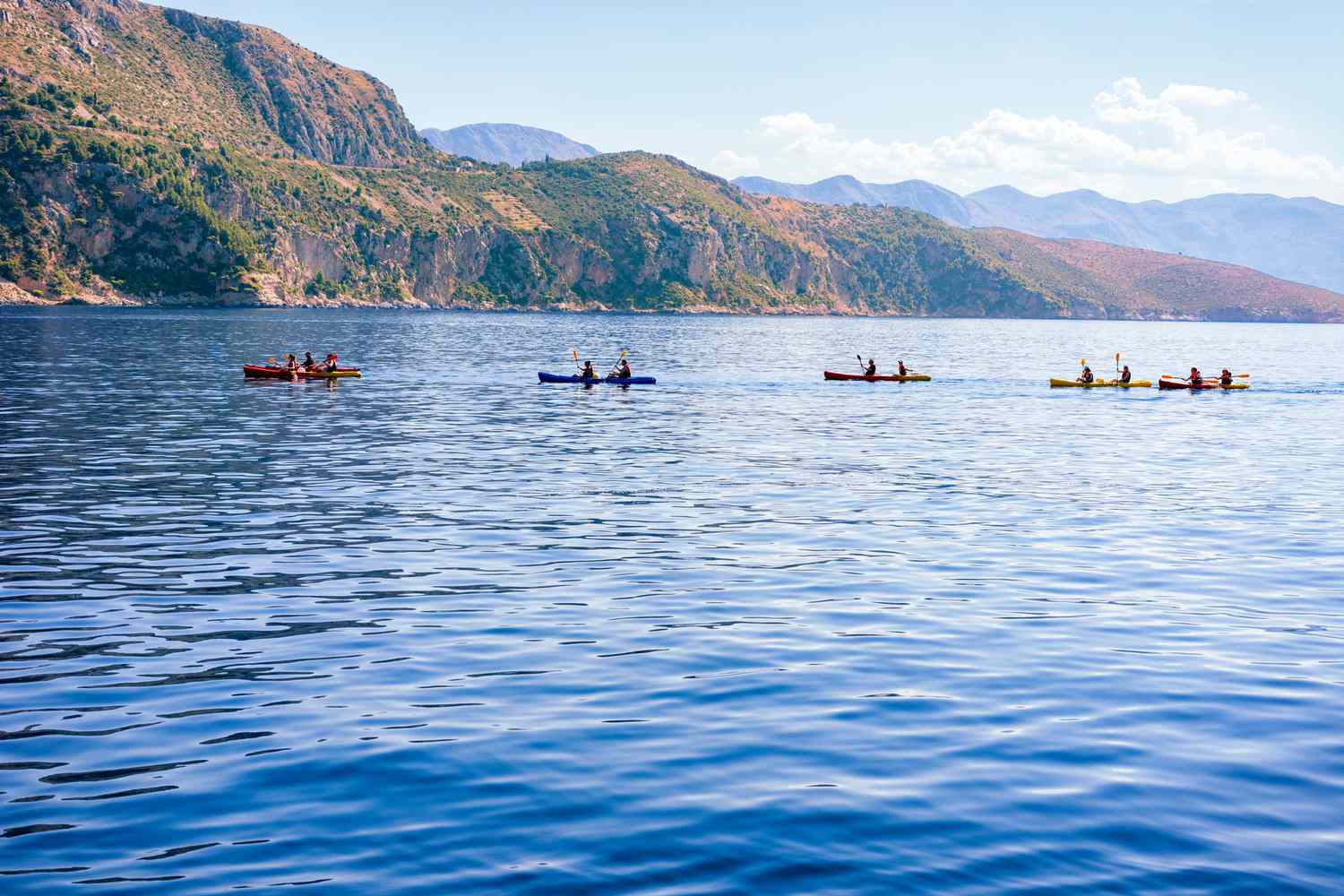 a line of five kayaks paddling in the Adriatic Sea off the Dalmatian Coast in Dubrovnik, Croatia