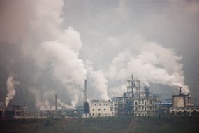 Cement factories with white plumes gas coming out of stacks