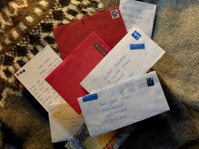 a stack of handwritten christmas cards to santa spilled on winter sweater