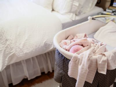 Bassinet with blankets next to a bed