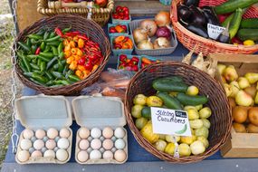 bright vegetables for sell at outdoor farmer market including cucumbers and eggs