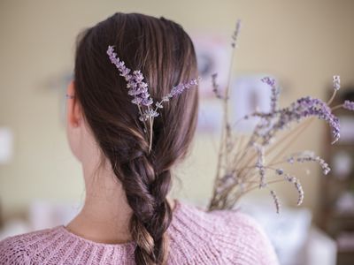 brunette woman with braided hair has fresh lavender sprigs tucked into braid and bouquet