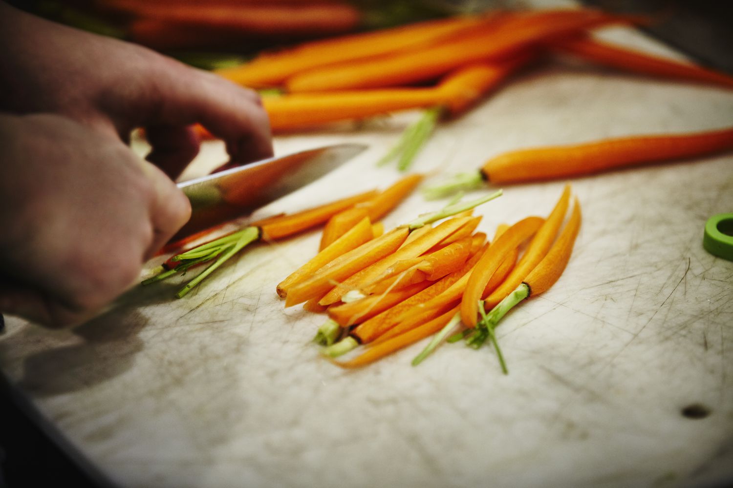 Man slicing carrots on cutting board in kitchen