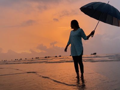 woman standing on beach with umbrella in Mumbai