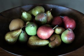 variety of pears in dark wooden bowl: asian, bartlett, anjou, seckel pears