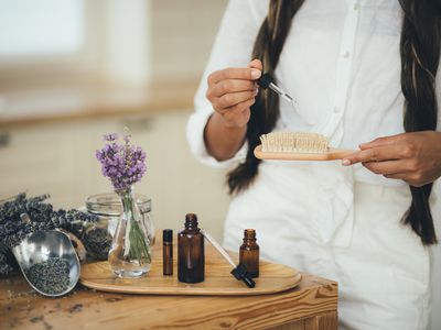 Young woman applying natural organic essential oil on hair and skin. Home spa and beauty rituals.